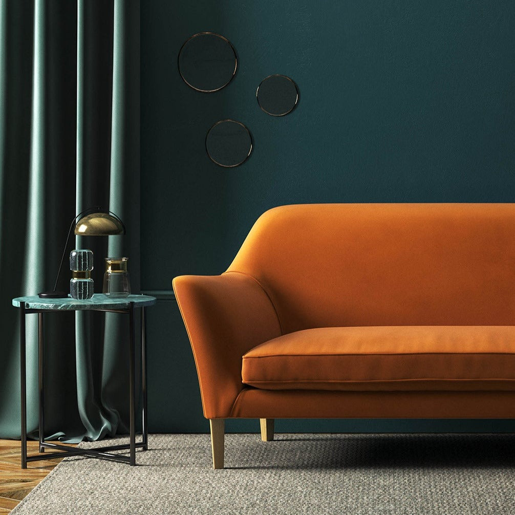 Sofa covered in a orange velvet upholstery fabric
