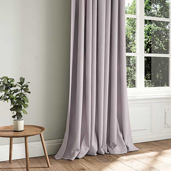 Serene bedroom featuring a lavender upholstered sofa, misty violet curtains, and soft pastel decor for a tranquil atmosphere.